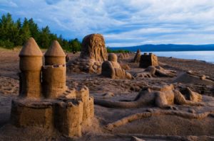 Sandcastles at Lesser Slave Lake, Alberta’s largest automobile accessible lake; in the background is the water, mountain silhouettes and trees.